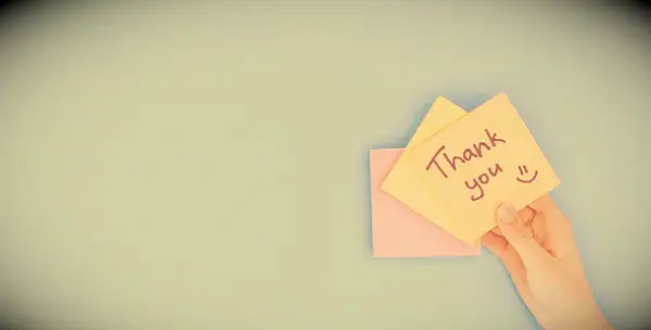 A hand holding a post-it note saying: Thank You!