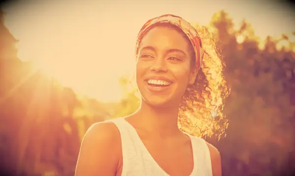 A smiling woman outside in the sunshine.