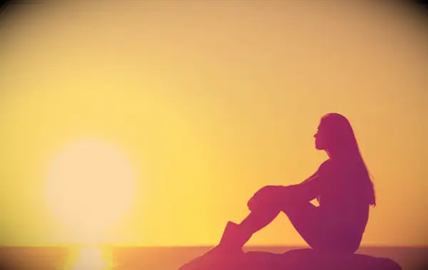 A woman looking at a sunset over the ocean.
