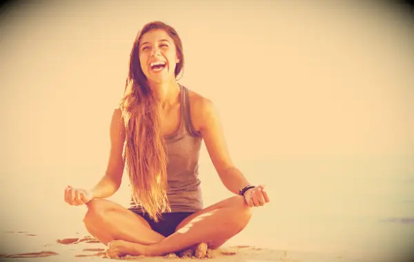 A happy woman sitting by the ocean.