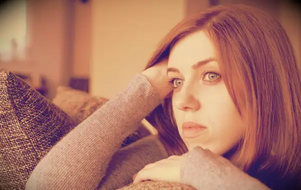 A woman looking sad while sitting on a couch.