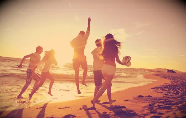 Friends having fun on a summer beach during sunset.