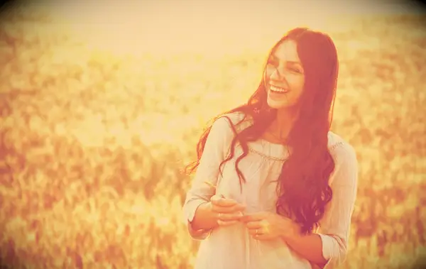 A happy woman smiling while standing in a field.