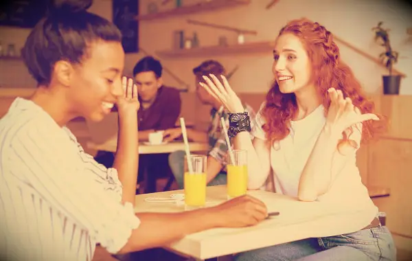Two girls having a good time in a cafe with juice glasses.