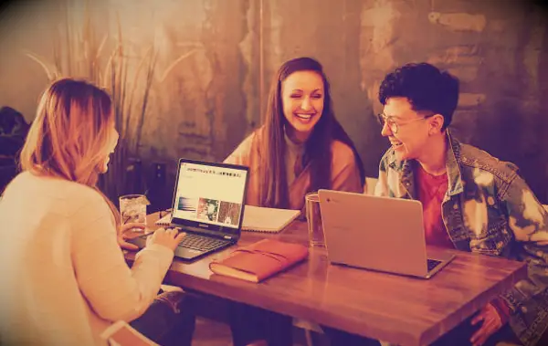 Three women with laptops having fun while working.