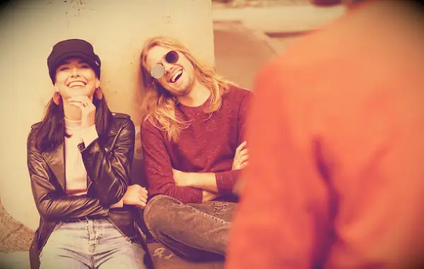 Friends laughing together while sitting outside.