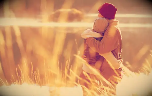 A couple embracing by a lake in the fall.