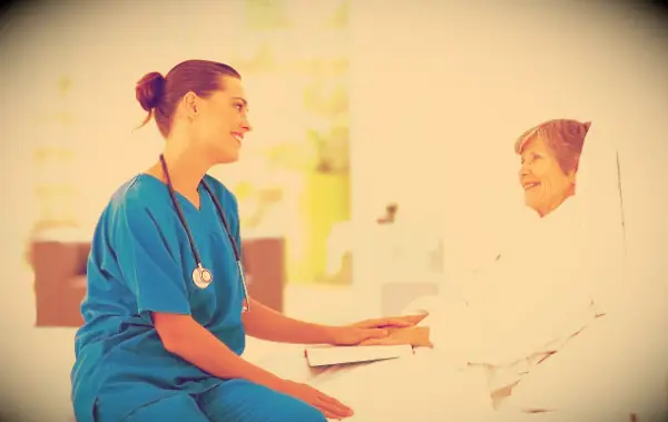 A nurse talking to a patient who is in a hospital bed.