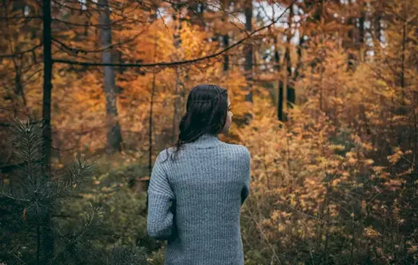 Woman walking on a trail through the foliage.