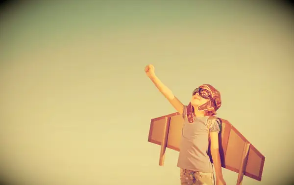 A child with wings looking up at the sky.